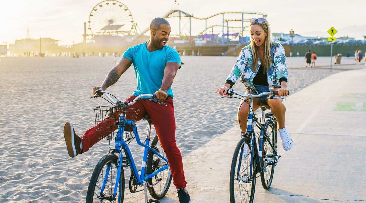 couple having fun riding bikes together at santa monica california