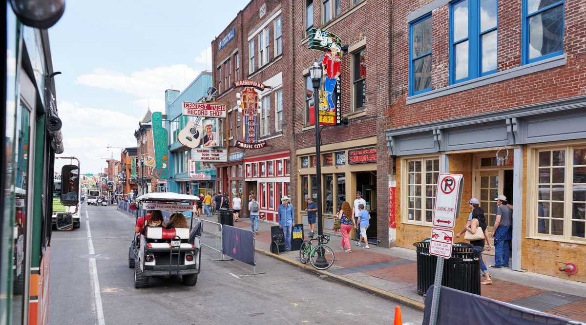 NASHVILLE, TN, USA - APRIL 14, 2017: Nashville's historic Broadway street, home to Ernest Tubb Record Shop, noisy and full of bars, entertainment, country music and visited by countless tourists on foot, in golf carts or busses.